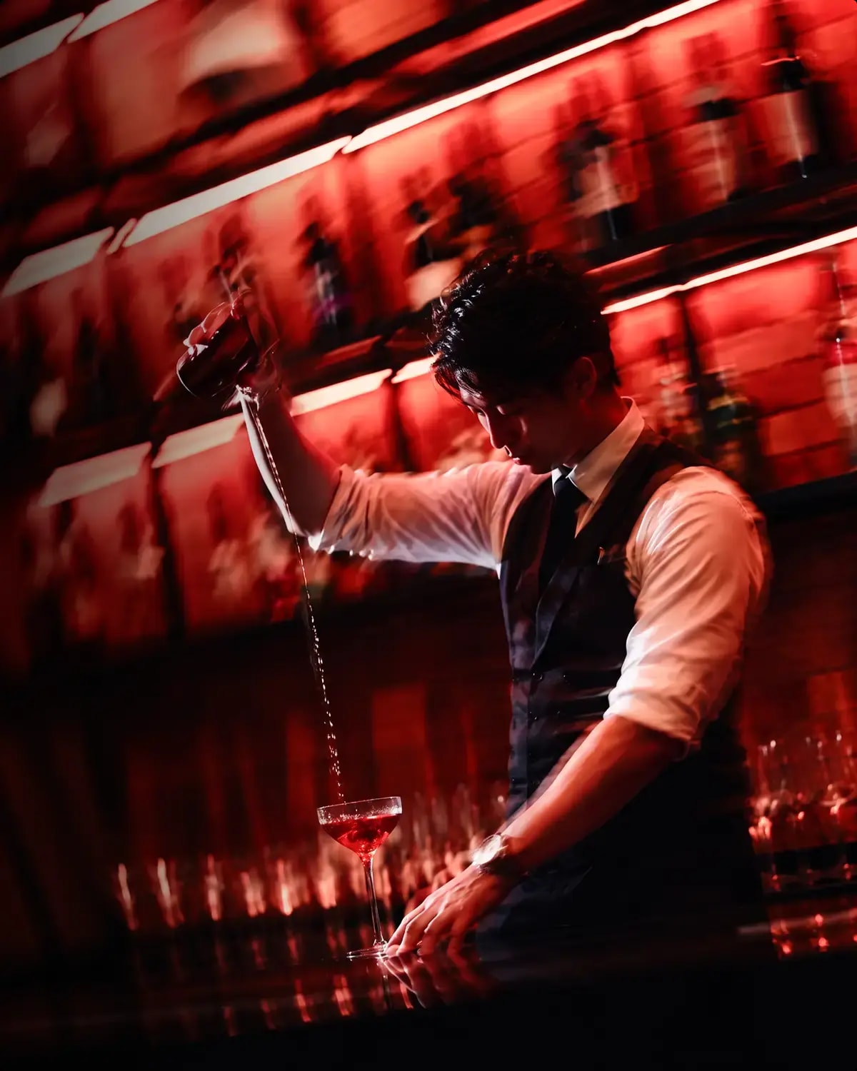 Bartender pouring a signature cocktail at AKA Lounge